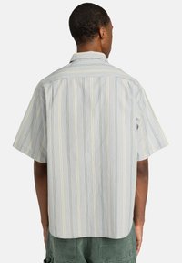 Short-sleeve shirt in a light gray fabric with vertical blue and yellow stripes, featuring a classic collar and a relaxed fit.