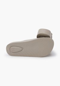 Beige gummisandal med struktureret tårem og formet sål, der har en rillede bund for bedre greb og størrelsesmærke 36 på bunden.