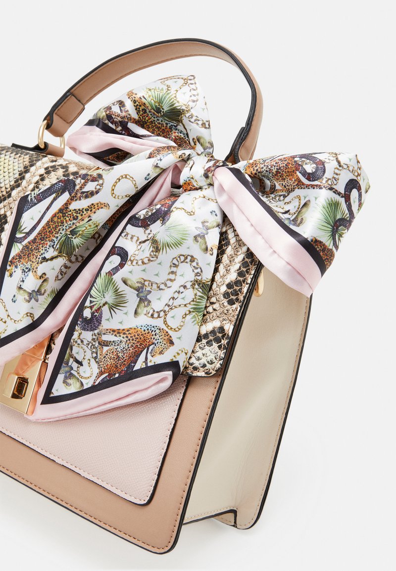 Sac à main beige et crème avec un rabat en texture de serpent, fermoir en or et une écharpe en soie nouée ornée de motifs léopard, serpent et feuille de palmier.