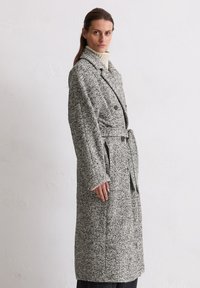 Grijs en zwart gestructureerd jassen van wolmix met een ceintuur in de taille, dubbele sluiting, brede revers en grote zijzakken.