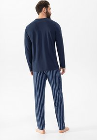 Haut à manches longues marine et pantalon de pyjama à rayures bleues. Tissu en coton, coupe décontractée, bandes latérales sur le pantalon, avec un dos uni sur le haut.