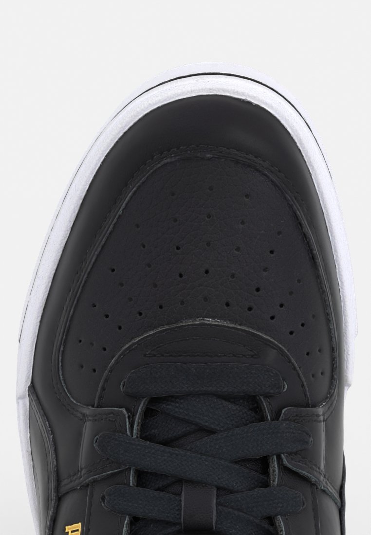 Baskets en cuir noir avec un bout arrondi, des perforations à l'avant et des lacets plats noirs. Semelle en caoutchouc blanche avec une bordure noire. Détail du logo doré.