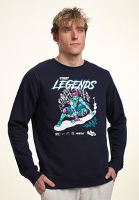 Felpa navy in cotone, caratterizzata da una grafica colorata di un personaggio con capelli rosa e un outfit turchese. Collo a giro e polsini a costine.