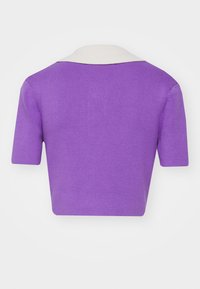 Pull court violet à manches courtes, texture côtelée, avec un col blanc contrastant, conçu pour une silhouette ajustée.