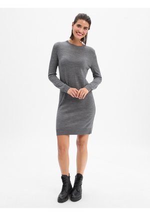 Robe en tricot grise à manches longues, col rond et poignets côtelés. Design droit, longueur genou, associée à des bottes noires à lacets.