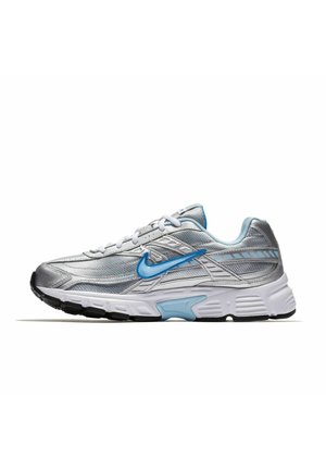 Zapatilla deportiva plateada y blanca con detalles en azul claro, con el logo azul de Nike swoosh y detalles en la suela negra.