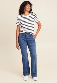 Gestreept t-shirt met korte mouwen; blauwe denim flarebroek met knoopdetails; witte sneakers; gladde stof en ontspannen pasvorm.