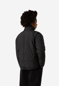 Μαύρο μπουφάν τύπου puffer με ψηλό γιακά, οριζόντιο κεντητό σχέδιο και άνετη εφαρμογή, με ελαστικές μανσέτες και λεία, γυαλιστερή υφή.