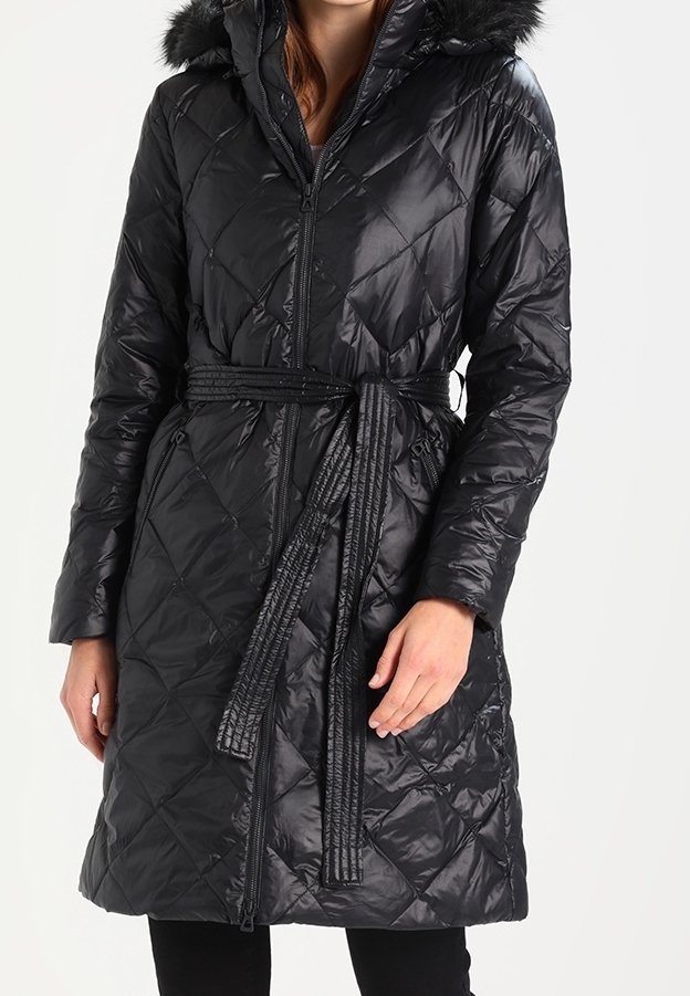 Svart vadderad puffjacka med dragkedja fram, bälte i midjan och en huva av konstpäls. Har en glänsande yta och diamantmönster över hela.