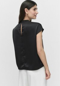 Sort satinbluse med korte ærmer, en nøglehul-rygdetalje og en afslappet pasform. Glat tekstur med minimalistisk design.