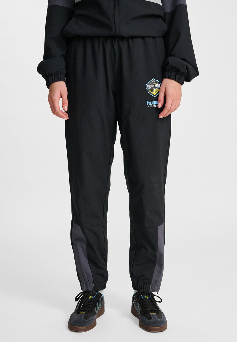 Svarta träningsbyxor med elastisk midja och muddar. Har grå sidopaneler och logotyper på vänster lår. Tillverkade av ett mjukt, lätt material.