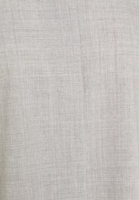 Tissu gris clair avec une texture tissée subtile et des fils fins entrecroisés créant un motif doux et naturel.