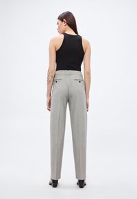 Hallid kohandatud püksid kõrge vöökohaga, laiade säärte ja kahe tagataskuga. Kangal on õrn muster ja sile tekstuur.