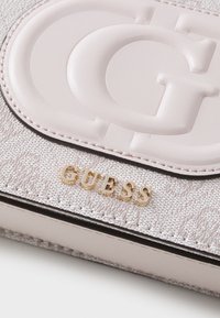 Portafoglio in pelle sintetica testurizzata rosa con logo impresso, scritta "GUESS" in oro e bordi neri. Presenta una superficie liscia e dettagli cuciti.
