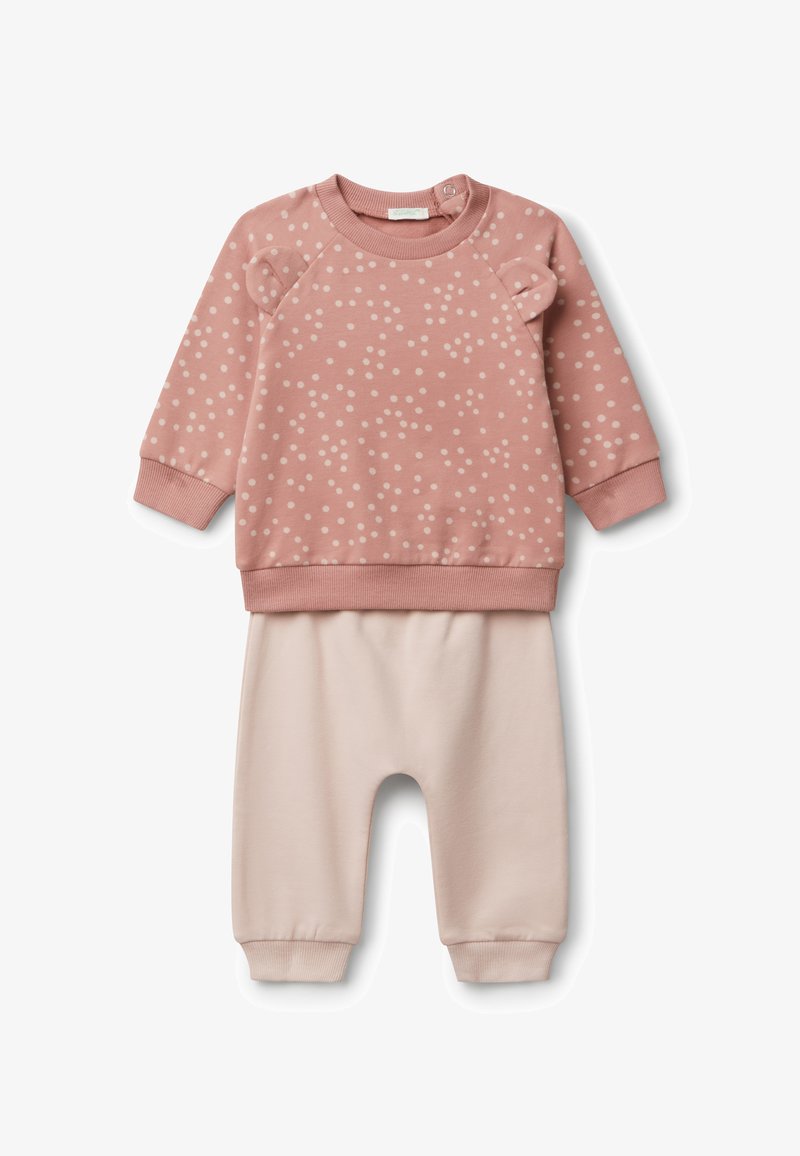 Dwuczęściowy zestaw dla niemowląt składający się z różowej bluzy w kropki z małymi uszkami na ramionach oraz jednolitych jasnoróżowych spodni z mankietami.