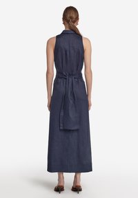 Lång marinblå linneskjortklänning med kragkrage, detaljer med knytning i ryggen och A-linjeform, med en stilren och slät textur.
