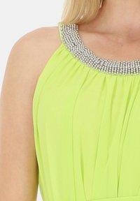 Neon zielona sukienka z plisowanym materiałem i srebrnym, koralikowym dekoltem. Gładka faktura z okrągłym, ozdobnym detalem kołnierza.