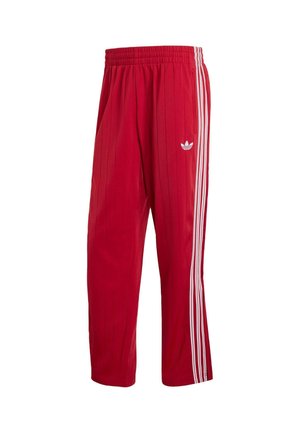 Pantalones deportivos Adidas rojos con cintura elástica, franjas laterales blancas y logo Trefoil en el muslo derecho sobre fondo blanco.
