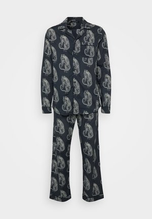 Navy pajama set featuring a repeating tiger pattern in white. The top includes a collar, buttons, and a chest pocket; the pants have a straight cut.