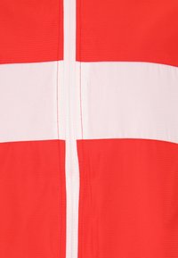 Giacca zip-up rossa e bianca con bold strisce orizzontali, tessuto testurizzato e cerniera centrale.