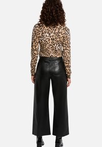 Leopardprint lange mouwen top gecombineerd met hoge taille zwarte leren wijde broek. Glad textuur en gestructureerde silhouet met zakken.