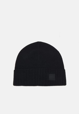 Black knit beanie with a ribbed cuff and a square rubberized logo patch. Soft texture and rounded top design.