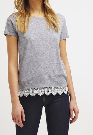 Szary t-shirt z krótkim rękawem z białą koronkową lamówką na dole. Materiał jest gładki i lekki, w połączeniu z ciemnymi dżinsami.