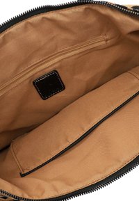 Brown fabric interior of a bag featuring a single zippered pocket, a large compartment, and a small leather logo patch. Smooth texture.
