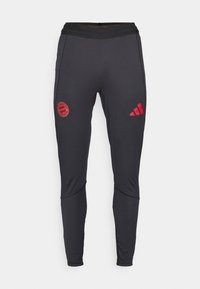Svarte treningsbukser laget av elastisk stoff. Har rød Bayern München-logo og tre striper-logo på siden. Elastisk midje for komfort.