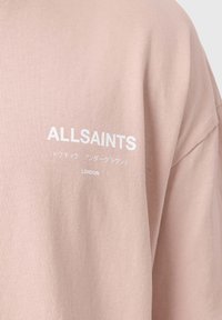 Ροζ βαμβακερό T-shirt με το λογότυπο «ALLSAINTS» σε λευκό, με επιπλέον κείμενο στα ιαπωνικά και τη λέξη «LONDON» τυπωμένη από κάτω.
