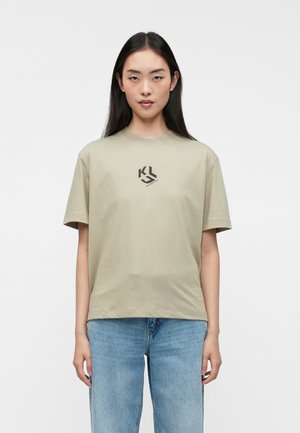 Khaki T-shirt with short sleeves, round neck, and a black logo on the chest; worn with blue denim jeans. Smooth cotton fabric.