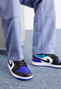 Černé a fialové tenisky s bílým logem, s hladkým koženým svrškem, vícebarevnými akcenty a texturovanou gumovou podrážkou.