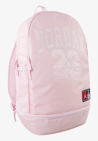Rosa ryggsekk med "JORDAN 23" brodert i hvitt, teksturert stoff, glidelåslommer og et merke med logo.