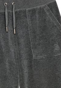 Grijze velours joggers met een trekkoord in de taille, voorzien van twee zijzakken en een klein geborduurd logo aan de linkerkant. Zachte, gladde textuur.