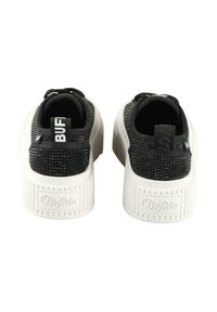 Black and white platform sneakers feature a textured knit upper, a cushioned sole, and a logo tag on the heel with a ridged design.