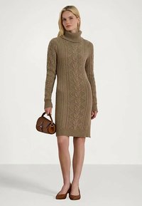 Bež pletena obleka z visokim ovratnikom in kabelskim detajlom, dolgi rokavi in ozek kroj. Usklajena z rjavim ročajem in usklajenimi petkami.
