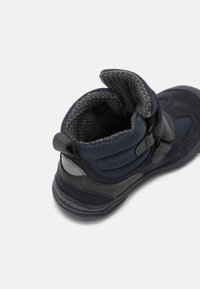 Botas de tobillo azul marino con un upper de ante texturizado y malla, que presenta un cuello de punto gris en contraste y correas laterales ajustables.