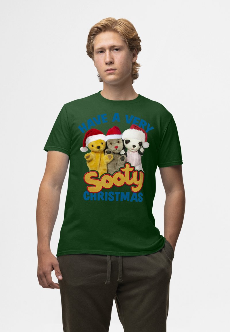 Grøn bomulds t-shirt med tre bløde karakterillustrationer iført røde julehætter, og teksten "HAV EN MEGET Sooty JUL" i gul og blå.