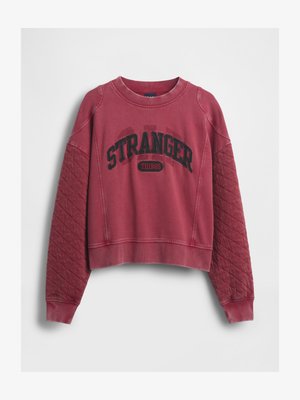Rode cropped sweatshirt met de tekst "STRANGER THINGS" in zwarte letters. Heeft een gewatteerde textuur op de mouwen en geribbelde manchetten en halslijn.