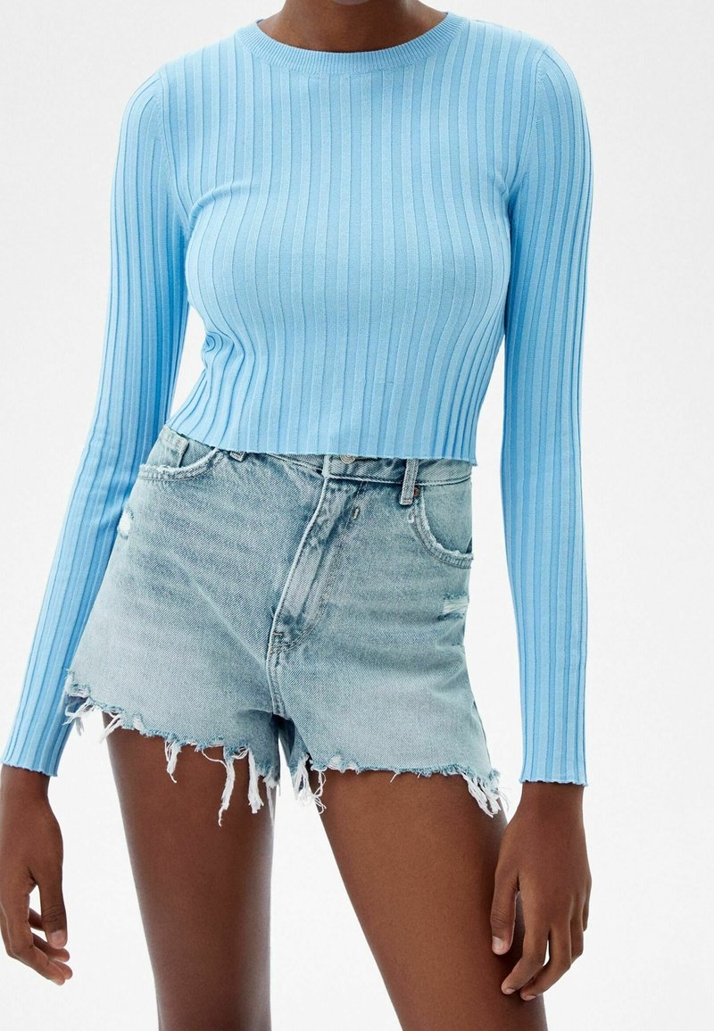 Light blue ribbed long-sleeve top paired with frayed light blue denim shorts, showcasing textured fabric and cropped design.
