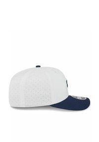 White perforated baseball cap with a navy blue curved brim and a small navy top button, shown from the side.