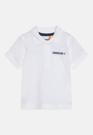 Polo shirt en coton blanc à manches courtes, avec une patte de boutonnage à trois boutons et "TIMBERLAND" brodé en bleu marine sur le côté gauche.