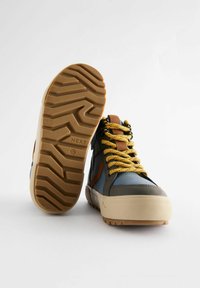 Hoge sneakers met een blauw en grijs bovenwerk met bruine accenten, gele gevlekte veters en een gestructureerde rubberen zool met een gepatterd profiel.