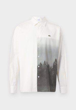 Chemise blanche à manches longues avec boutons, ornée d'un paysage forestier en niveaux de gris imprimé sur le côté droit avant et d'un petit logo de crocodile vert.