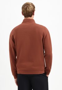 Bruine fleece pullover met een hoge kraag en lange mouwen; gladde textuur en casual pasvorm, met een band onderaan de zoom.
