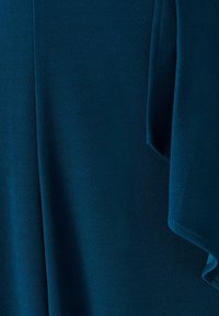 Tela verde azulado con textura suave y diseño drapeado. Presenta pliegues suaves y bordes limpios, creando una apariencia fluida.