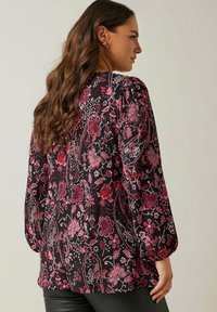 Sort blomsterbluse med tekstureret stof, detaljerede rosa og røde blomstermønstre samt ballonærmer. Velegnet til afslappet brug.