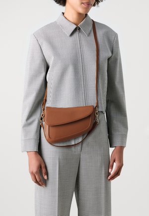 Sac bandoulière en cuir marron avec une surface texturée et une fermeture à rabat, doté d'une longue bandoulière réglable et d'accents métalliques.