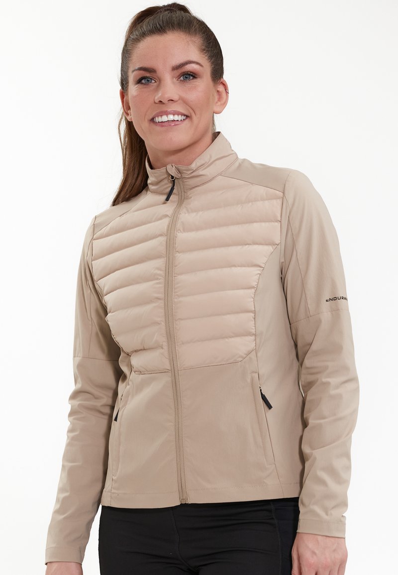 Beige isolerad jacka med dragkedja fram, med horisontellt quiltade sektioner på bröstet och slät tyg på ärmarna och sidorna.