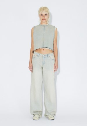 Top corto in denim azzurro chiaro e jeans a gamba larga, con orlo grezzo, cuciture classiche e vestibilità rilassata. Abbinati a sneakers chiare.
